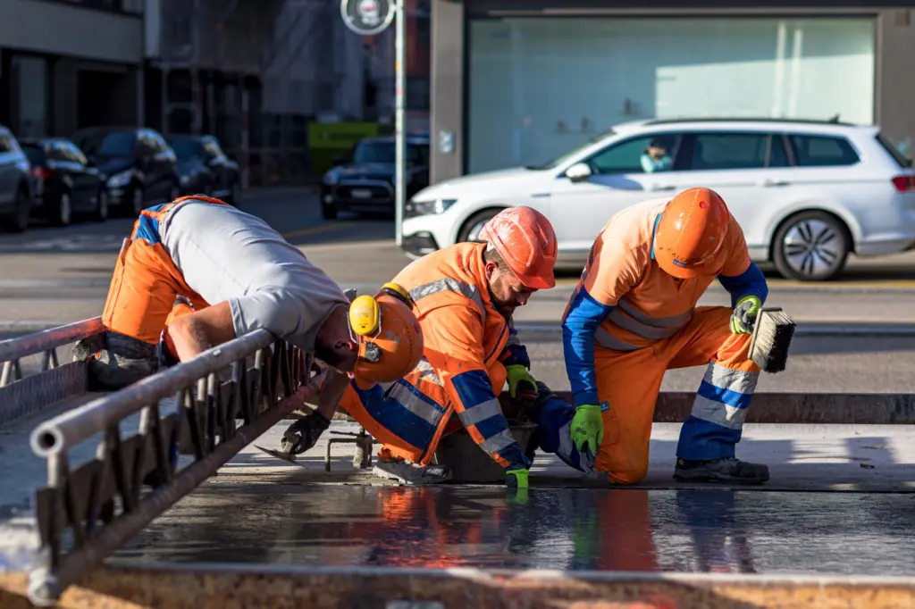 Instandstellung & Revision BP Station Wiedikon drei Straßenbauer bei der Asphaltierung